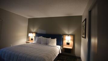 A hotel room with a large bed, two bedside lamps, a headboard, and a framed picture on the wall.