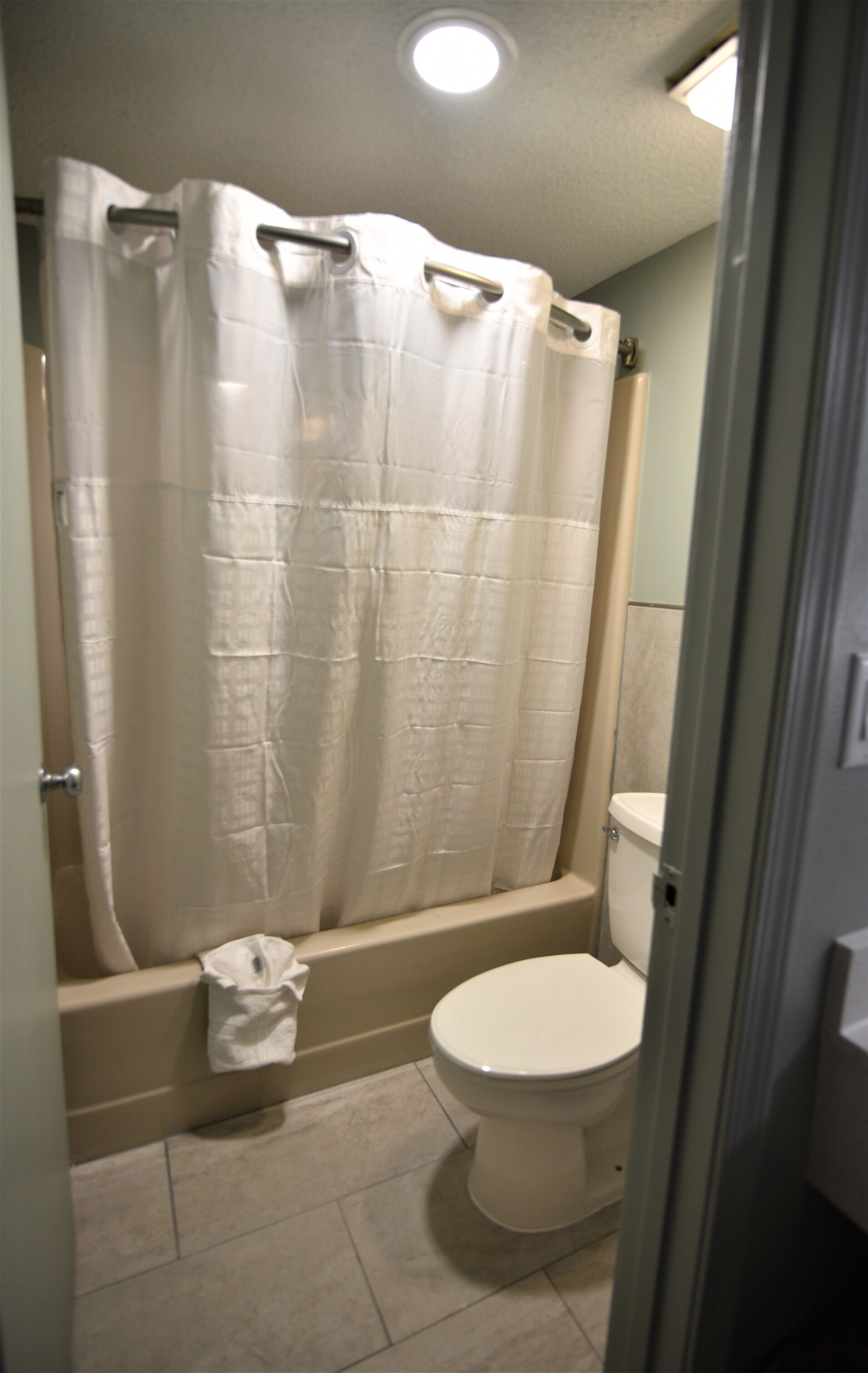 A bathroom with a shower curtain, a bathtub, and a toilet.