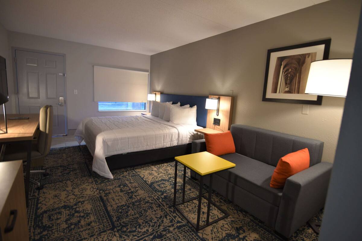 Een hotelkamer met een bed, een bank, een bureau en een bijzettafeltje.