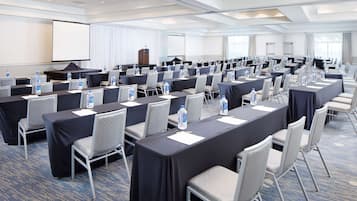Un salón de conferencias con filas de mesas y sillas, equipado con botellas de agua y tarjetas de identificación.