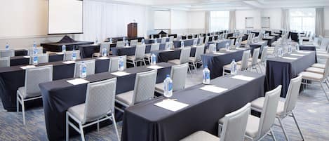A conference room with rows of tables and chairs, equipped with water bottles and nameplates.
