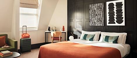 A modern hotel room with a large bed, a desk, a chair, and a window.