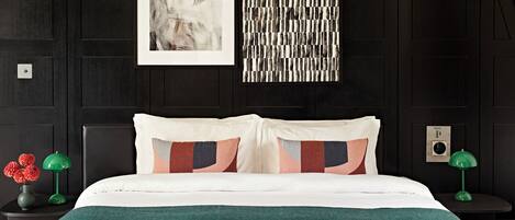 Une chambre moderne avec un mur recouvert de panneaux en bois foncé, un grand lit avec une literie de couleur turquoise, deux tables de chevet avec des lampes vertes et une œuvre d’art abstraque encadrée au-dessus du lit.
