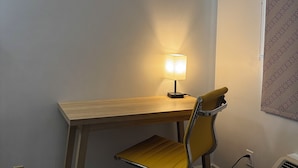 A workspace with a wooden desk, a yellow chair, a desk lamp, and a wall-mounted air conditioner.