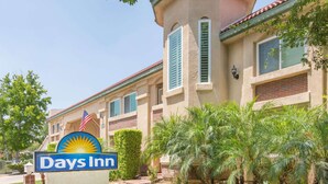 A Days Inn hotel with a sign, palm trees, and a brick facade.