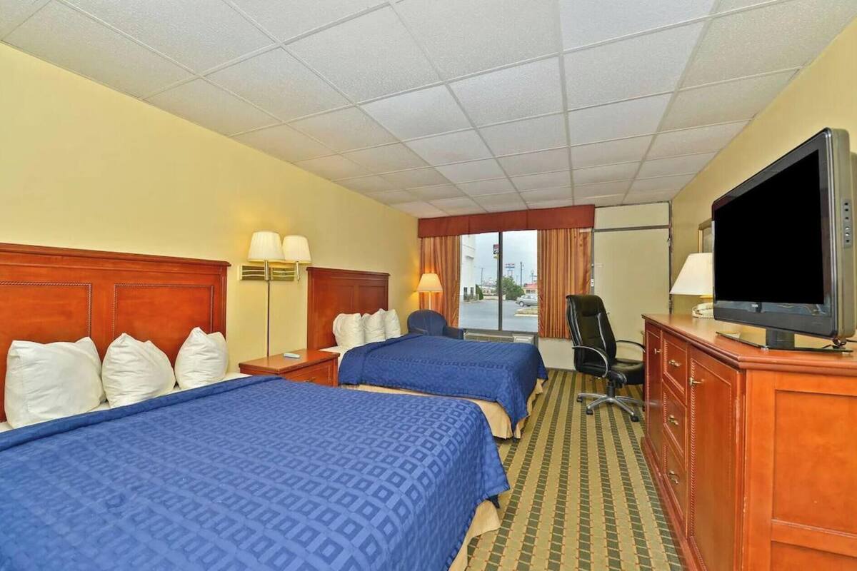 A hotel room with two beds, a television, a desk, and a chair.