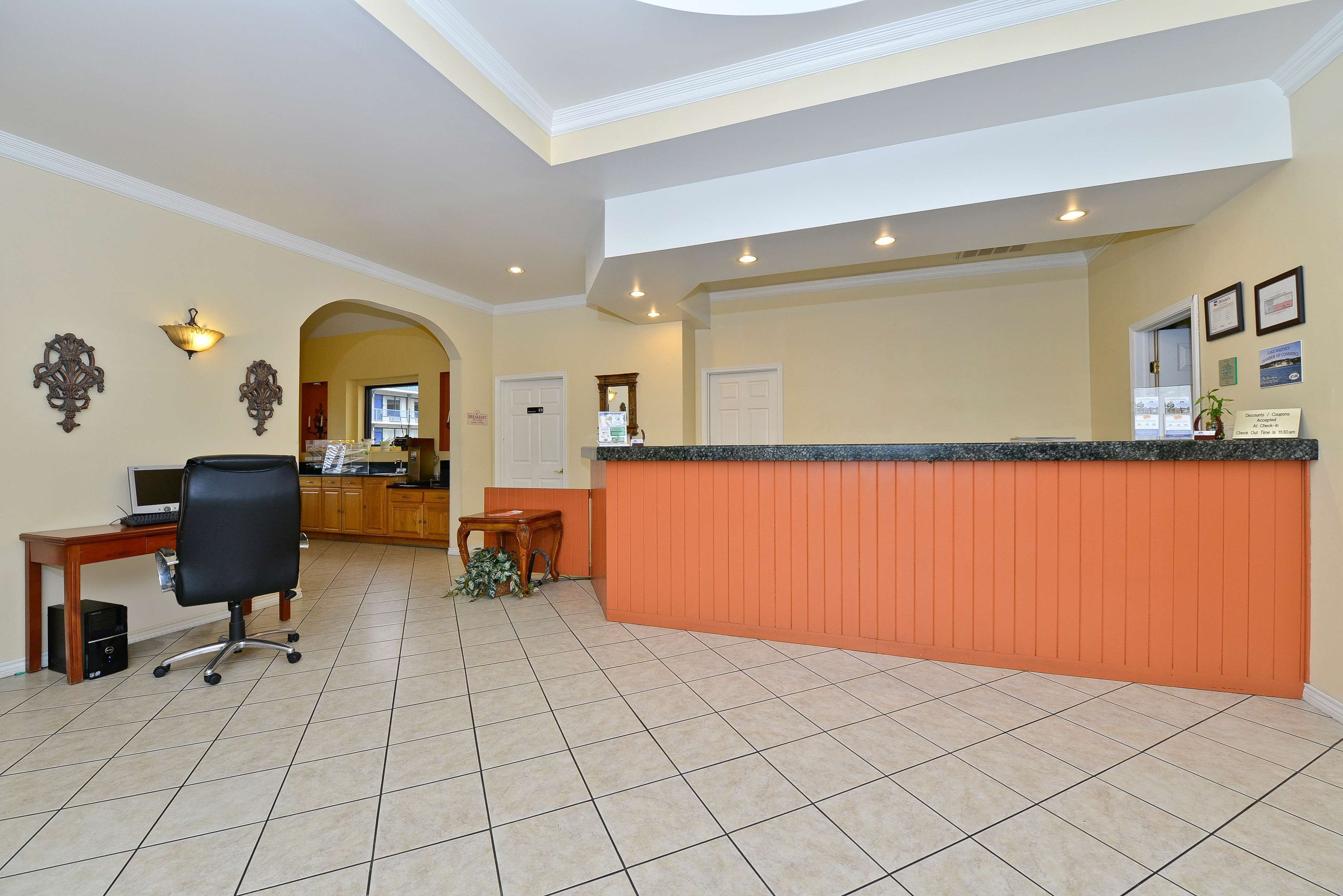 A reception area with a counter, a desk with a computer, and a chair.