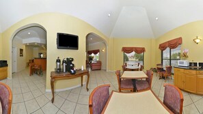 A spacious dining area with a high ceiling, a television mounted on the wall, and a kitchen area with a microwave and coffee maker. - Americas Best Value Inn Hillsboro (Hillsboro)