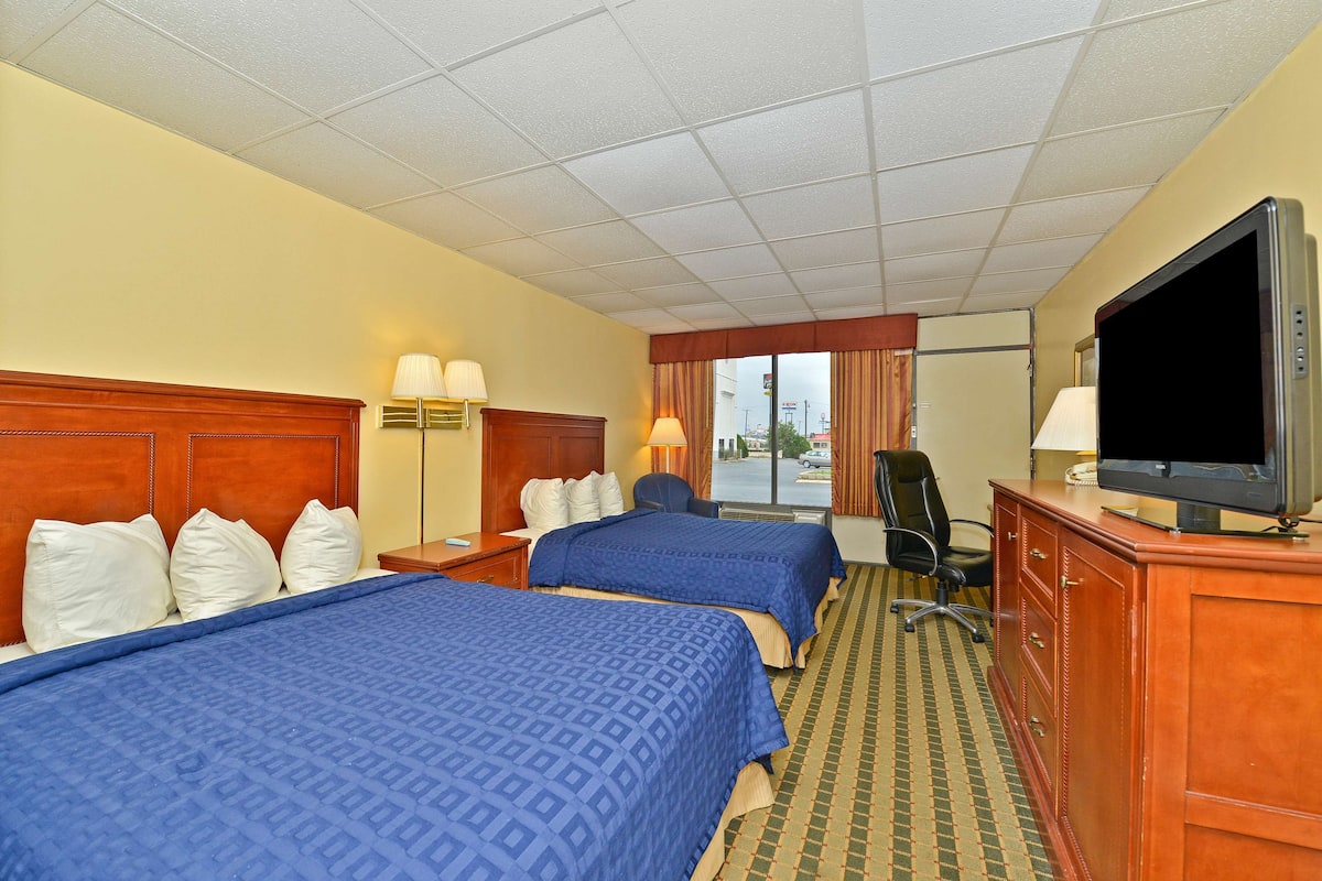 A hotel room with two beds, a television, a desk, and a chair.