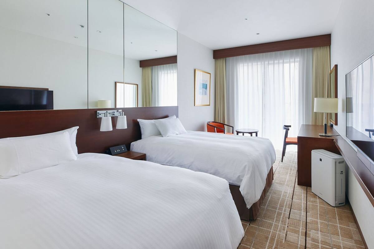 Une chambre d’hôtel avec deux lits, un bureau, une chaise, une télévision et un mini-bar.