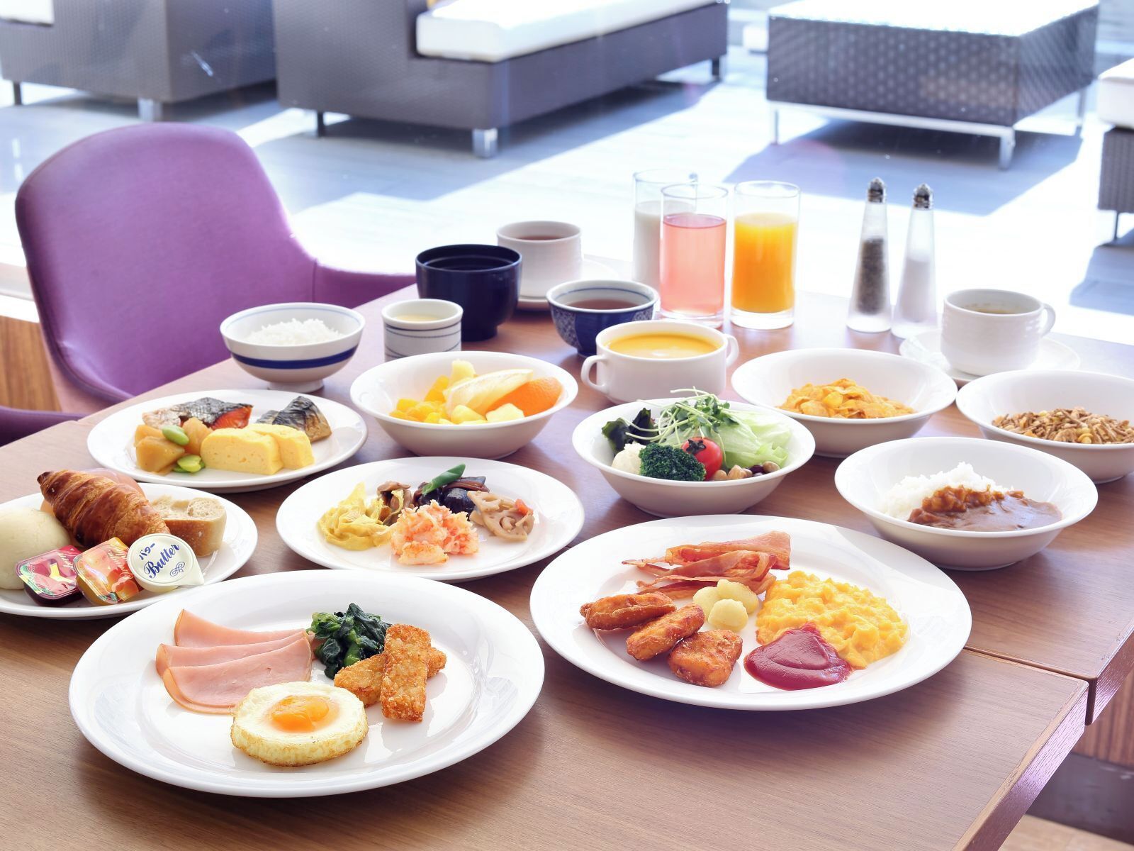 A breakfast buffet with various dishes, drinks, and condiments.