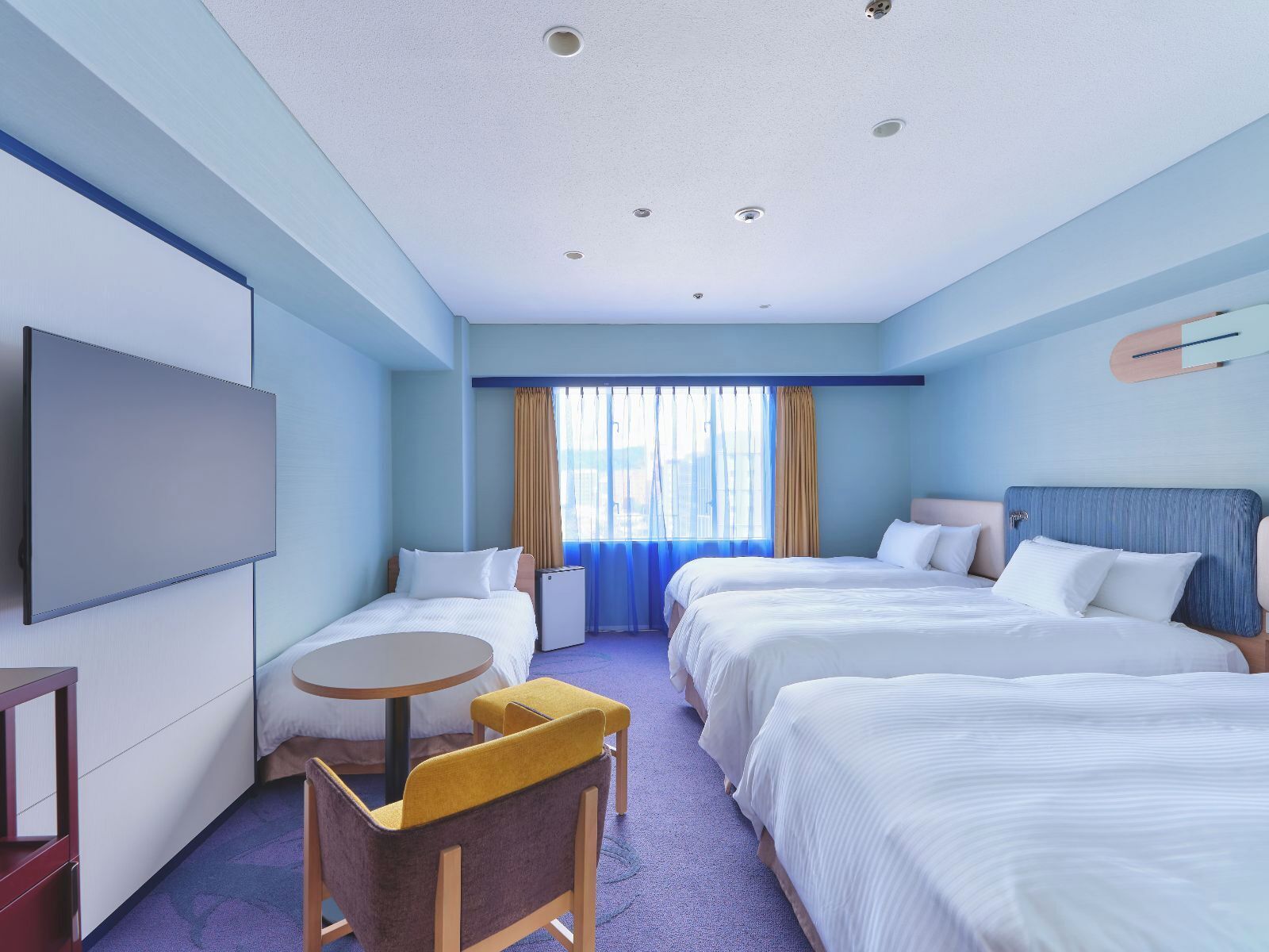 A hotel room with two beds, a TV, a small table, and a chair.