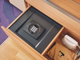 A drawer with a black device, a white phone, and a brown bag with a logo.