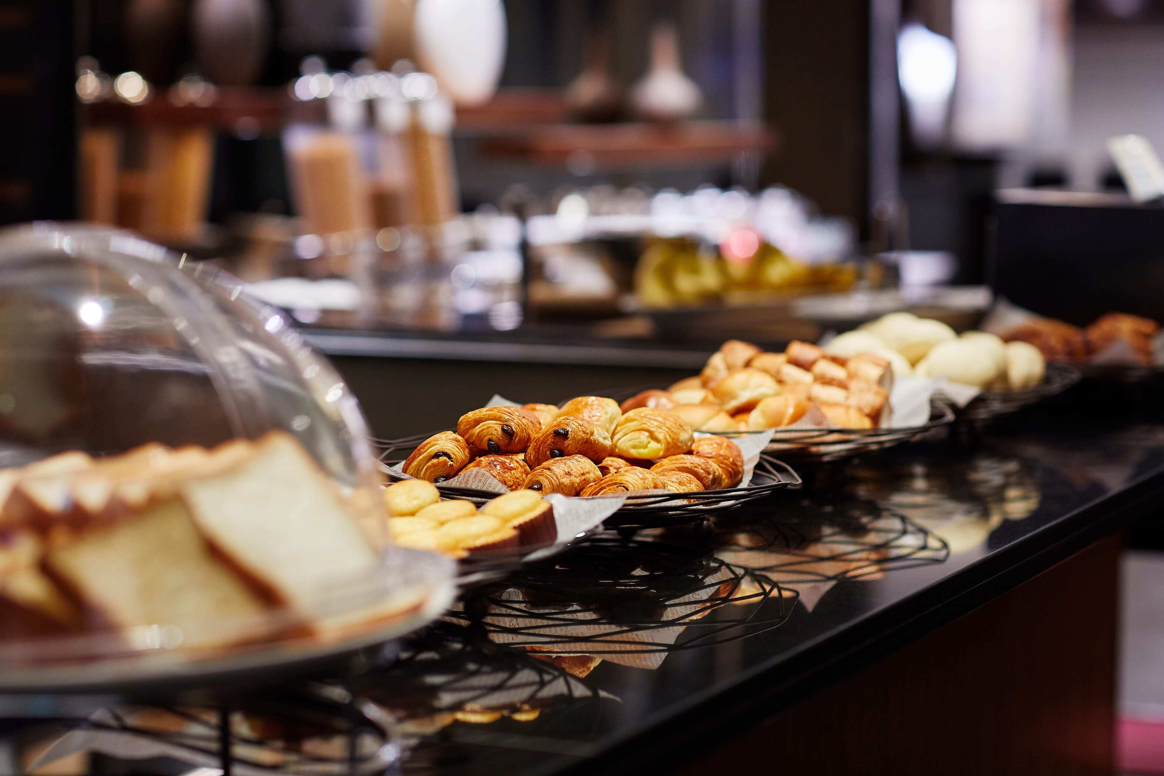 Un bufé con diversas opciones de panadería, incluyendo pasteles y pan.