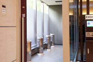 A modern restroom with a glass partition and a money exchange machine.