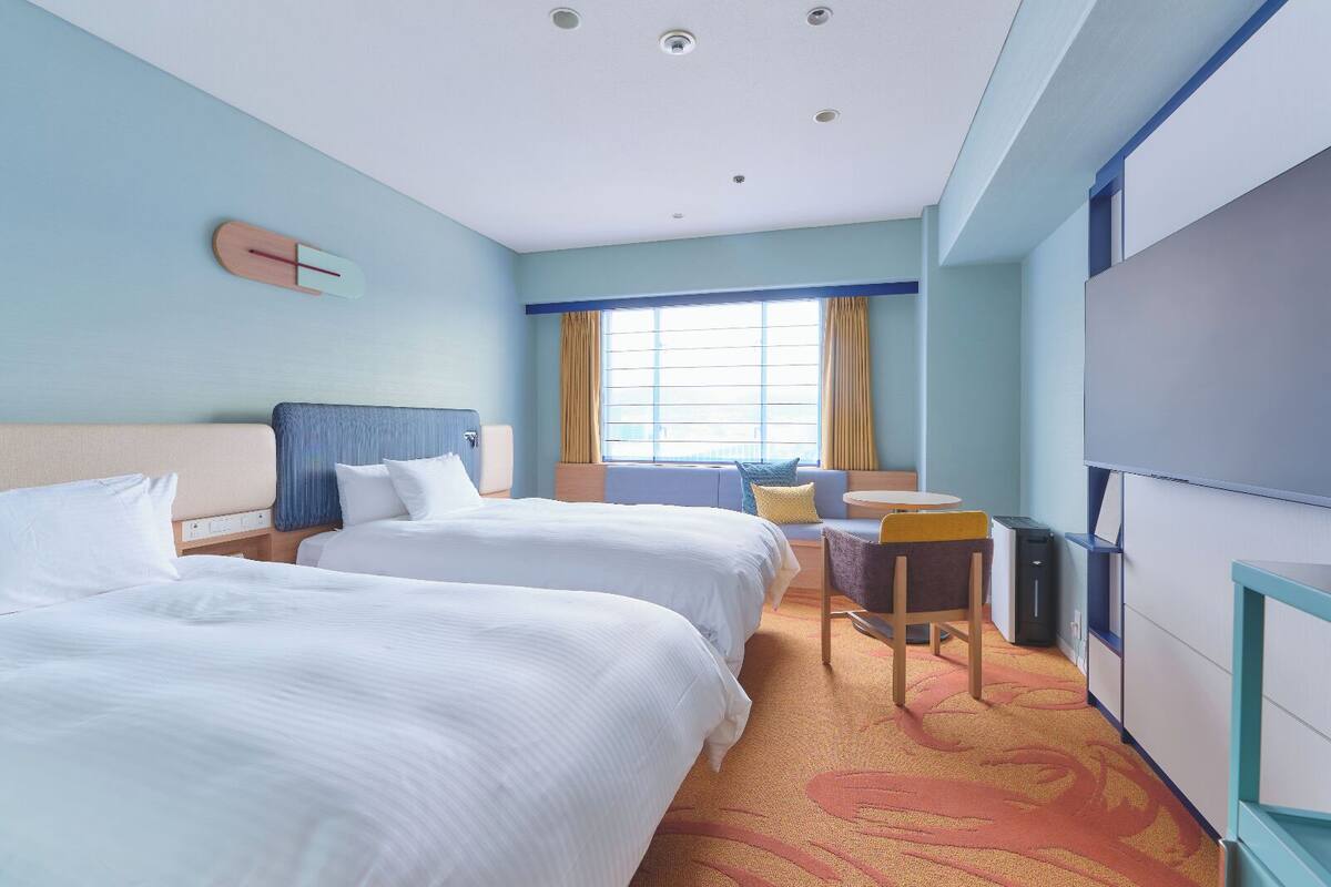 Une chambre d’hôtel avec deux lits, un canapé, une petite table et un téléviseur.