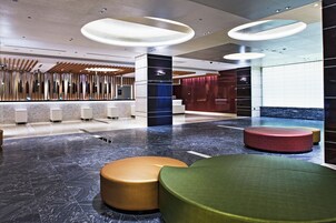 A modern lobby with a reception desk, seating areas, and a marble floor.