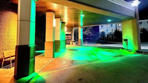 A gas station at night with illuminated green lights and a clear view of the gas pumps.