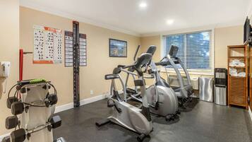 Et fitnesscenter med løbebånd, crosstrainere og styrkeudstyr.