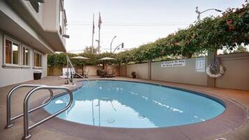 Una piscina al aire libre, sillones reclinables de piscina