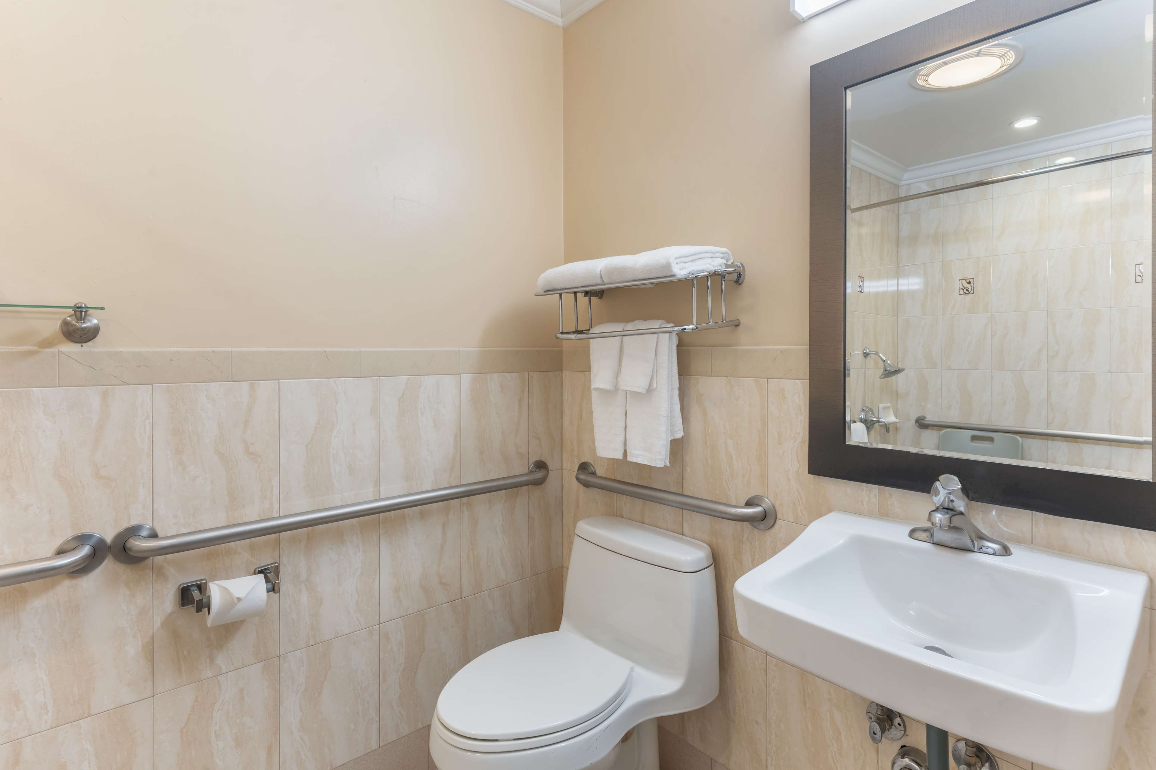 Une salle de bain équipée de toilettes, d’un lavabo, d’un miroir et d’un porte-serviettes.