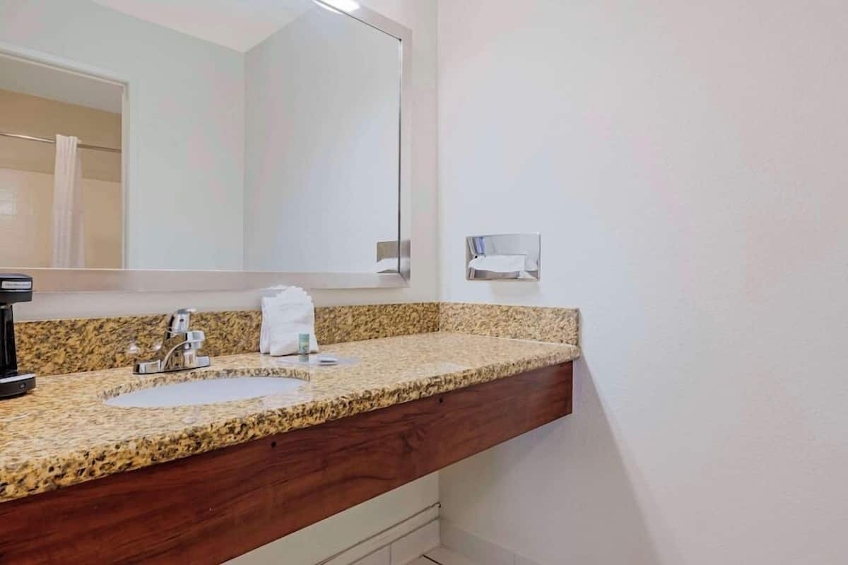 A bathroom with a granite countertop, a sink, a mirror, and a towel rack.