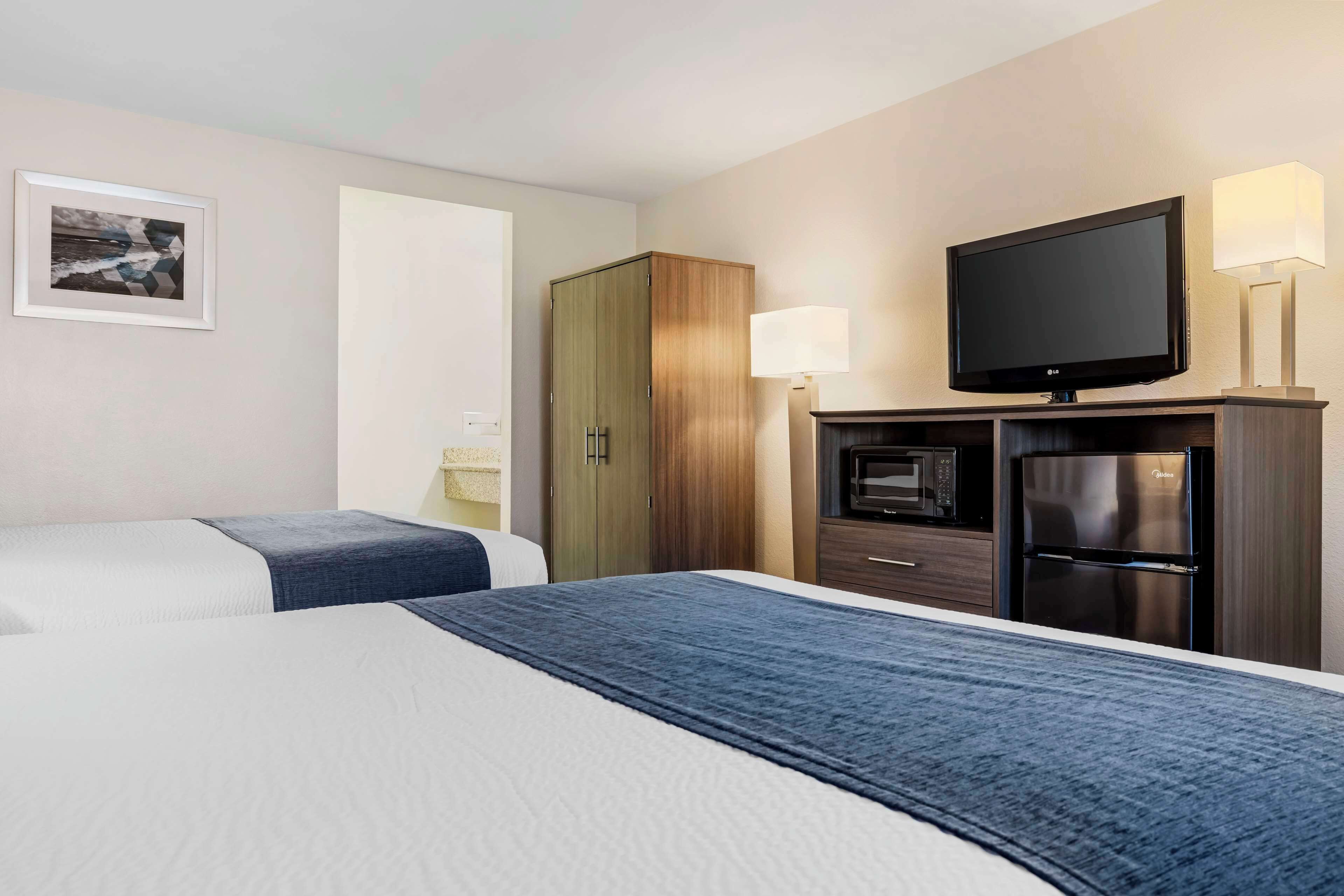Habitación de hotel con dos camas, televisión, refrigerador y microondas.