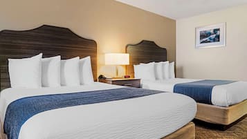 Een hotelkamer met twee bedden, een nachtkastje met een lamp en een lijst aan de muur.
