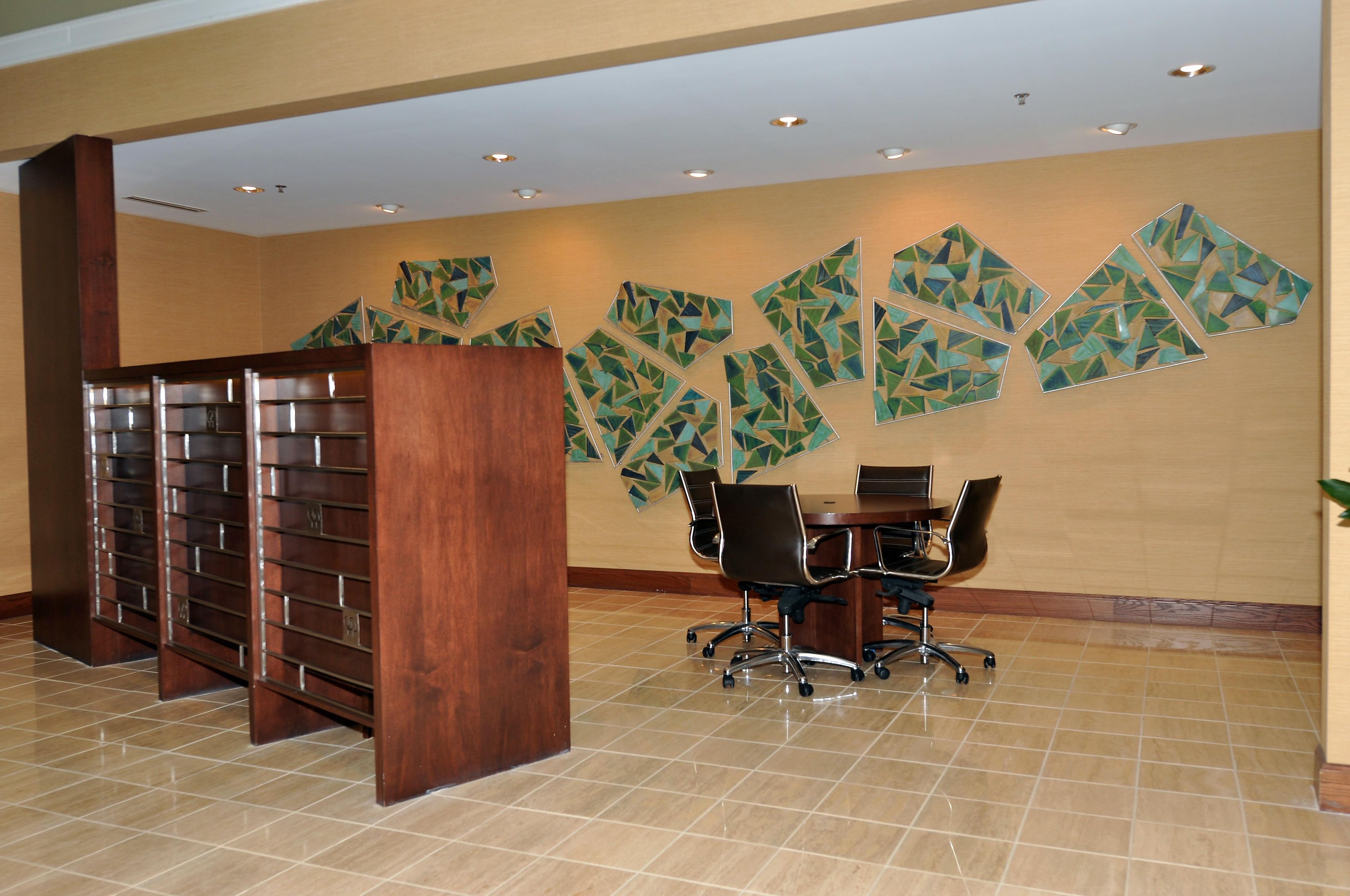 Une salle de conférence dotée d’un comptoir d’accueil en bois, d’un sol carrelé et d’un mur orné d’œuvres d’art aux motifs géométriques.