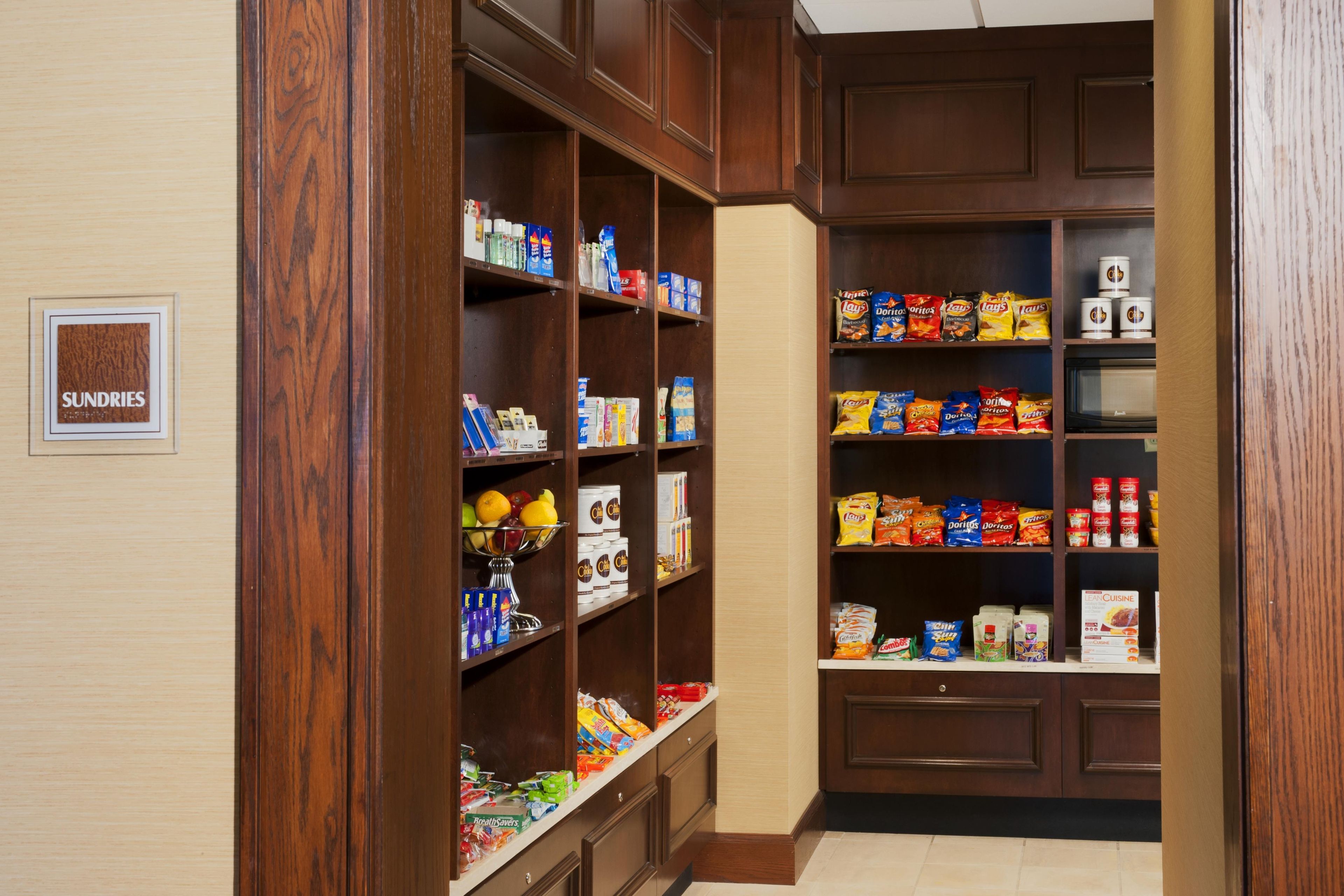 A pantry with shelves stocked with various food items, including snacks, beverages, and condiments.