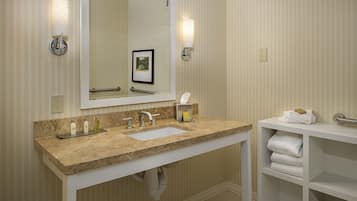A bathroom with a marble sink, a large mirror, a towel rack, and a shelf with folded towels.