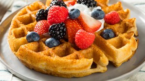 Un plato de gofres belgas cubiertos de frutos rojos y crema batida.