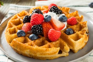 Un piatto di waffle belgi ricoperti di frutti di bosco freschi e panna montata.