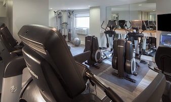 Una palestra con diverse attrezzature per esercizi, tra cui tapis roulant, vogatore e pesi liberi.