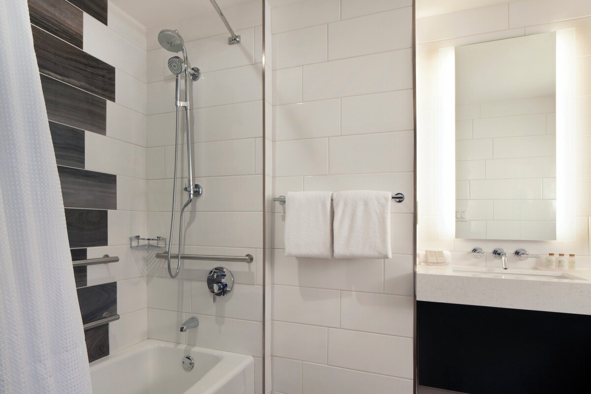 Un bagno moderno con vasca, doccia e mobile lavabo con specchio.