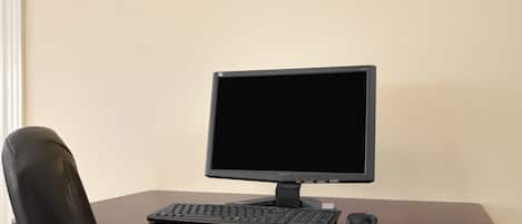 Un escritorio de madera con un monitor negro, teclado y ratón.