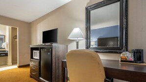 A hotel room with a desk, a television, a lamp, a mirror, and a coffee maker. - Hammock Hotel Lancaster PA (Lancaster)