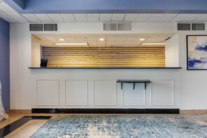 A reception area with a wooden reception desk, a black and white tiled floor, and a blue and white patterned rug. - Hammock Hotel Lancaster PA (Lancaster)