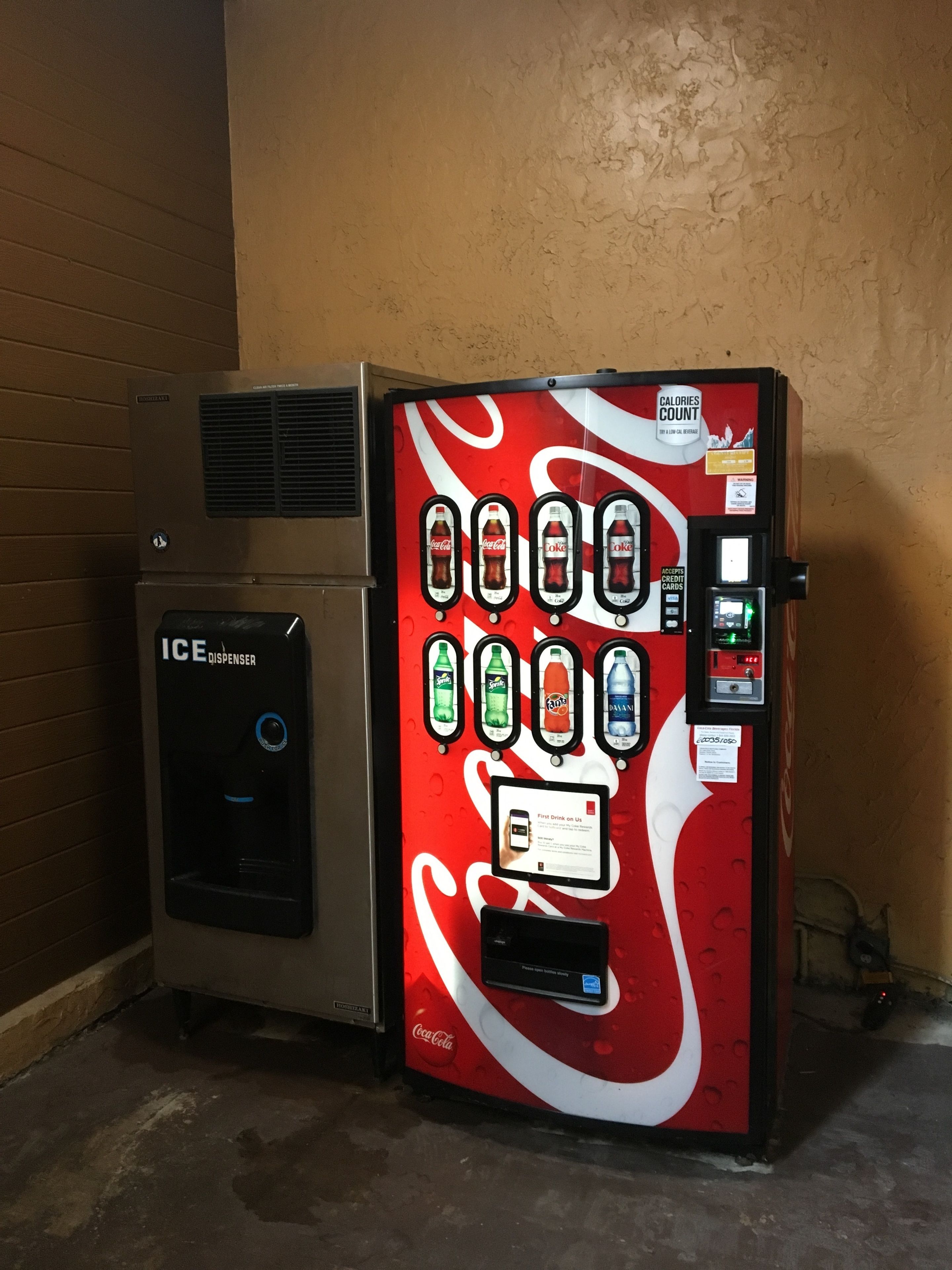 A vending machine with a Coca-Cola logo, an ice dispenser, and a digital display.