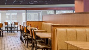 A restaurant with wooden tables and chairs, a wooden partition, and a view through large windows. - Days Inn by Wyndham St Augustine/Historic Downtown (St. Augustine)