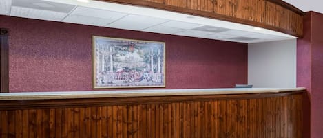 Un mostrador de recepción con diseño de panel de madera, una obra de arte enmarcada encima y una encimera blanca.
