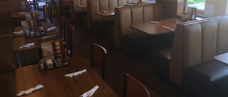 L'intérieur d'un restaurant, avec des banquettes et des tables, certaines étant équipées de serviettes et de condiments.