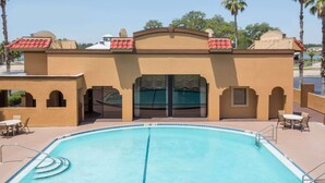 A pool area with a clear blue pool, a covered seating area, and a building with a red-tiled roof. - Days Inn by Wyndham St Augustine/Historic Downtown (St. Augustine)