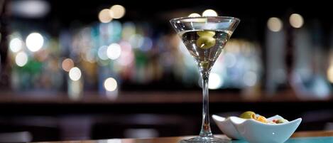 Una copa de martini con una rodaja de limón sobre una barra.