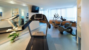 Un gimnasio moderno con cintas de correr, elípticas y máquinas de pesas.