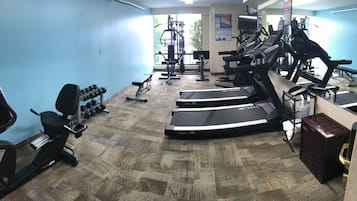 Une salle de sport équipée de tapis de course, d’haltères et d’appareils de musculation.