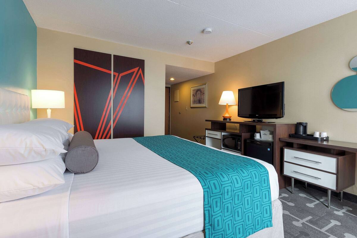 Une chambre d’hôtel équipée d’un lit, d’un bureau, d’une télévision et d’une salle de bain.