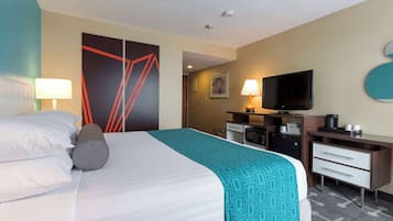A hotel room with a bed, a desk, a television, and a bathroom.