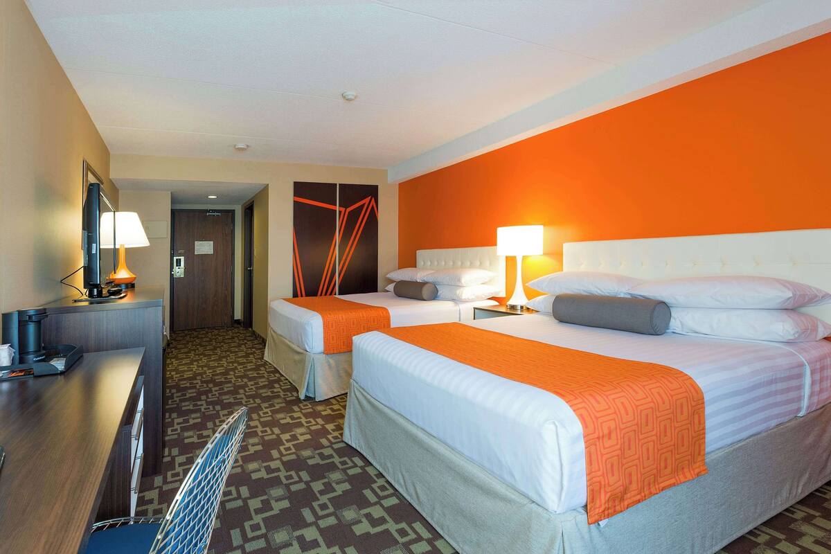 Une chambre d’hôtel avec deux lits, un bureau et une télévision.