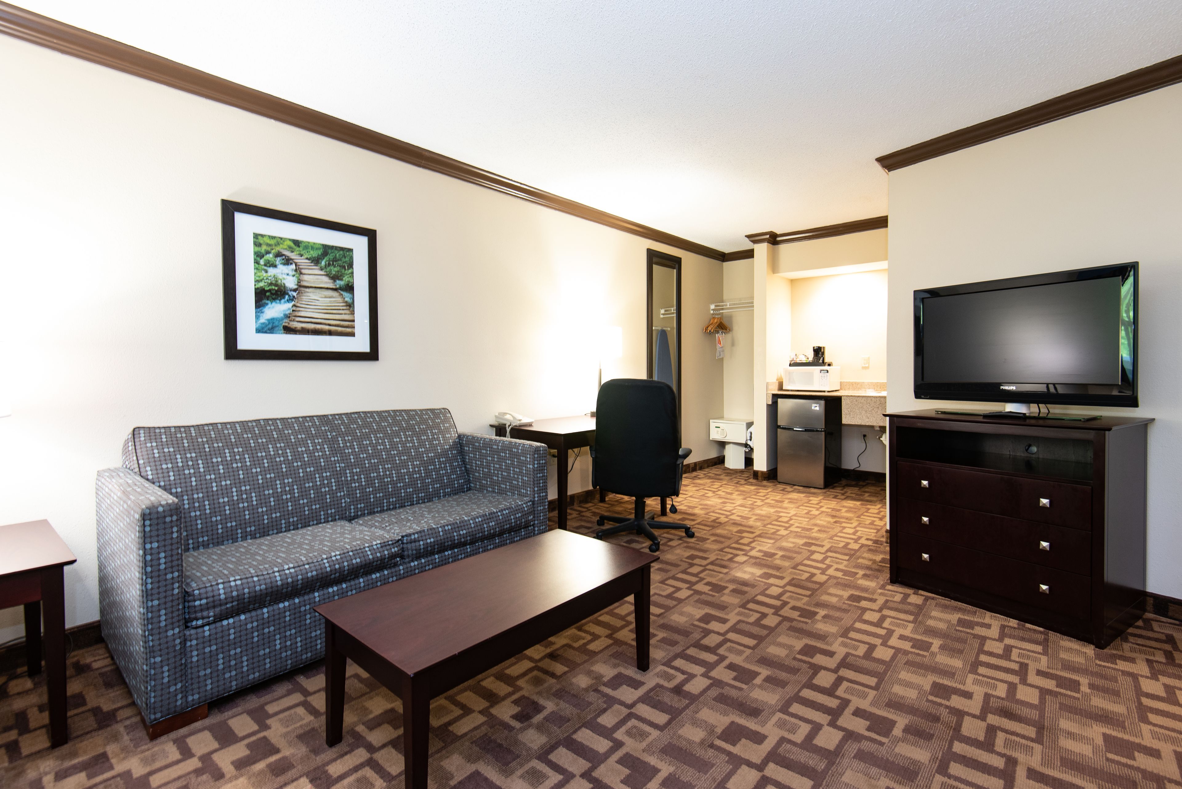 Habitación de hotel con sofá, mesa de centro, televisión, escritorio y microondas.